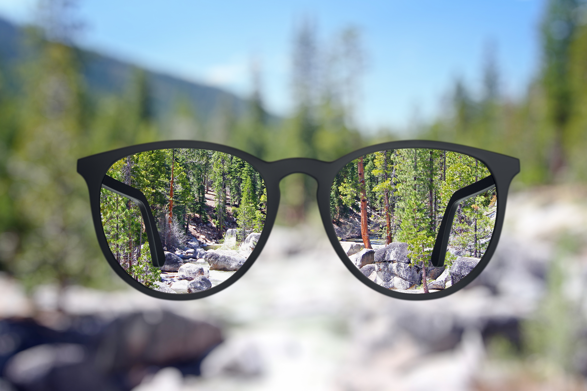 Paisagem borrada ficando nítida através das lentes de um óculos de grau — visão corrigida pela assinatura Visão Fixa